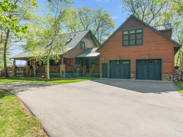 view of front of house with asphalt driveway, an attached garage, covered porch, and metal roof