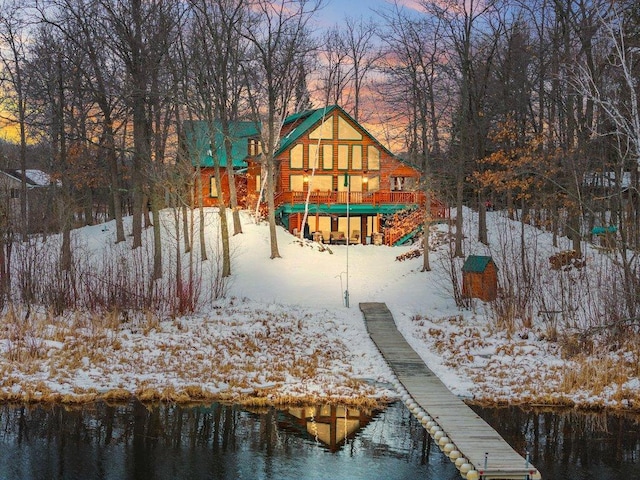 snow covered back of property with a water view