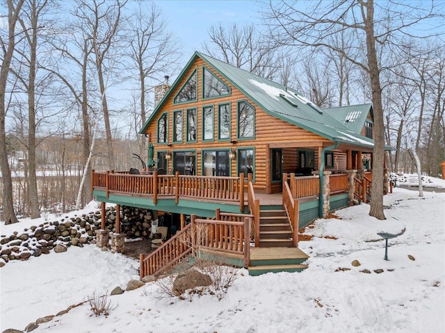 chalet / cabin with stairway, covered porch, a chimney, and metal roof