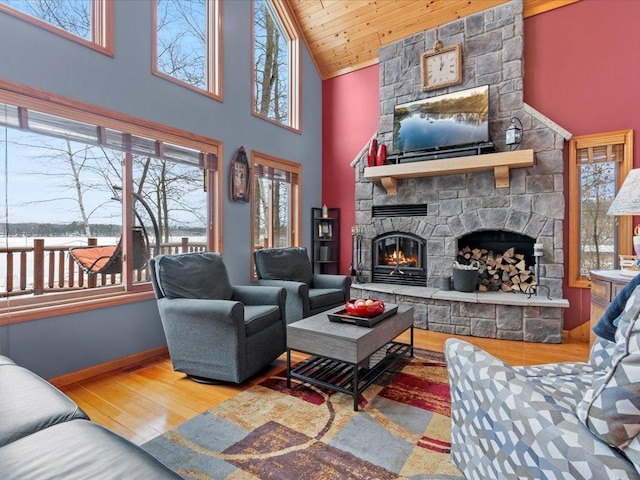 living room featuring a fireplace, wood finished floors, high vaulted ceiling, and baseboards