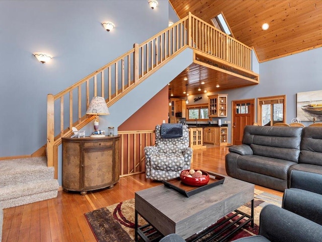 living area featuring high vaulted ceiling, hardwood / wood-style floors, stairway, and wood ceiling