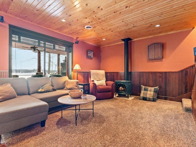 living room featuring a wainscoted wall, a wood stove, wood ceiling, recessed lighting, and wooden walls