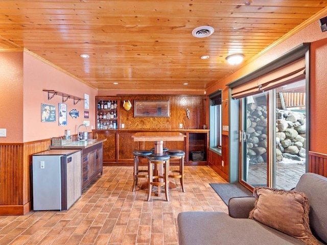 kitchen with wood walls, a wainscoted wall, plenty of natural light, wooden ceiling, and brown cabinetry