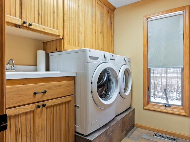 laundry area featuring cabinet space, separate washer and dryer, and baseboards