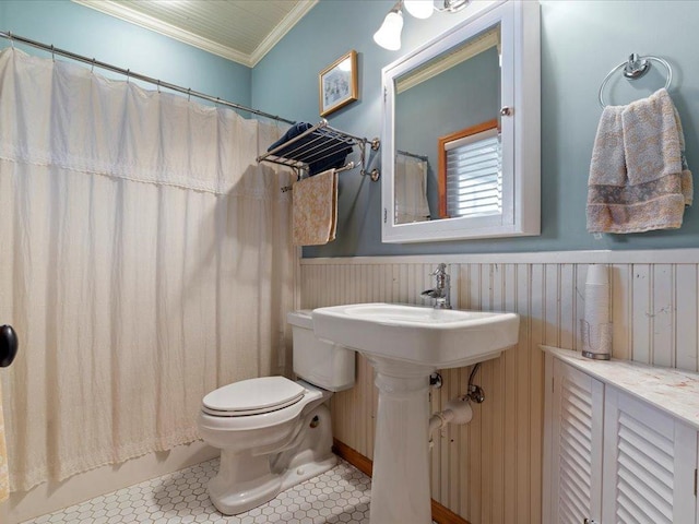 full bathroom featuring wainscoting, toilet, crown molding, curtained shower, and tile patterned floors