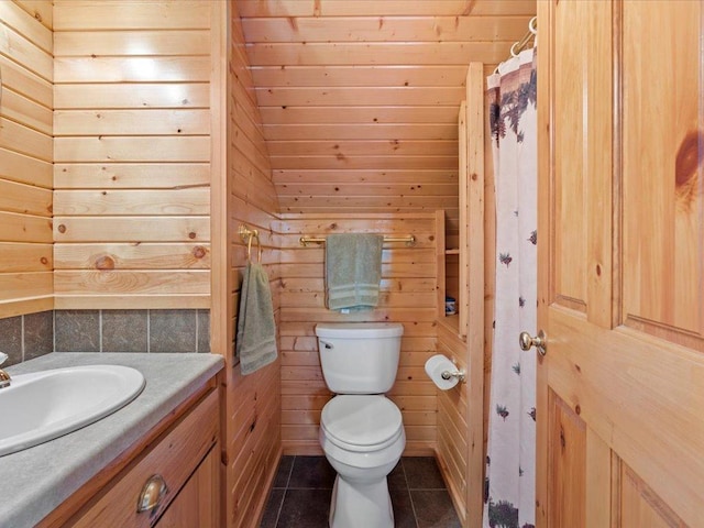 bathroom featuring toilet, tile patterned floors, wood walls, and vanity