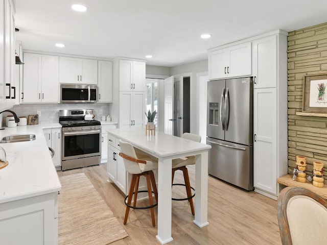 kitchen featuring stainless steel appliances, a sink, light countertops, and white cabinets