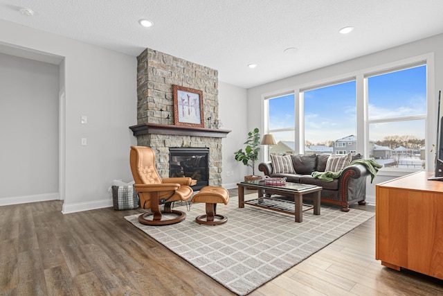 living room featuring wood-type flooring, a textured ceiling, and a fireplace