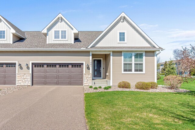 view of front of house with a front lawn, asphalt driveway, a garage, and a shingled roof