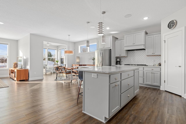 kitchen with appliances with stainless steel finishes, gray cabinetry, a kitchen island, dark wood finished floors, and recessed lighting