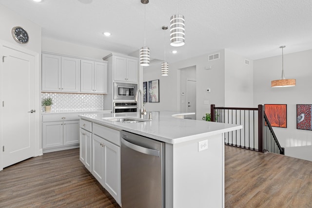 kitchen with stainless steel appliances, dark wood-style floors, light countertops, decorative backsplash, and white cabinets