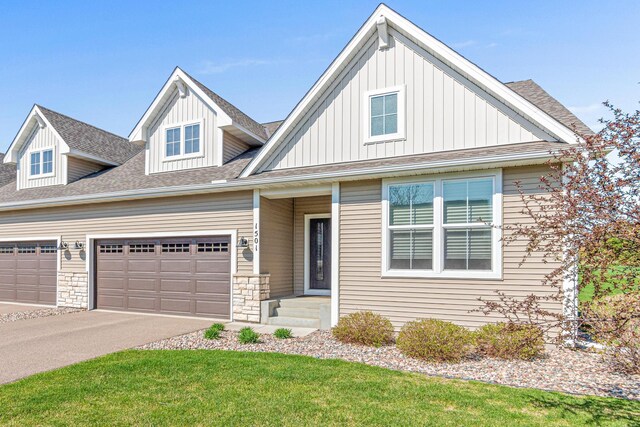 view of front of house with board and batten siding, a garage, roof with shingles, driveway, and a front lawn