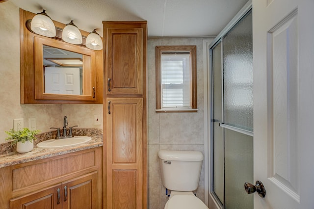 bathroom featuring a shower with door, vanity, and toilet