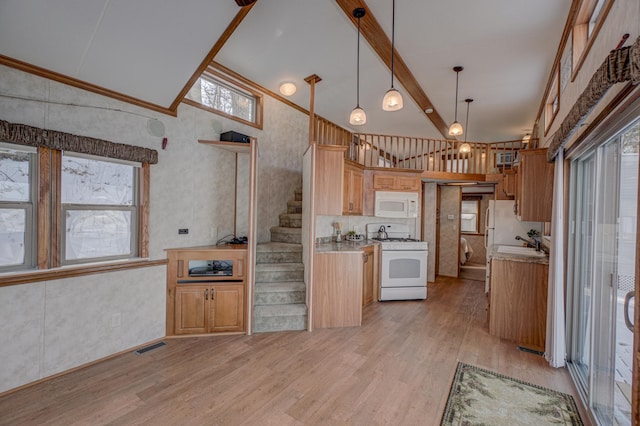 kitchen featuring sink, white appliances, hanging light fixtures, light hardwood / wood-style floors, and beamed ceiling