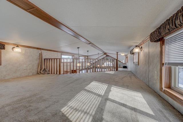 carpeted spare room with vaulted ceiling and a textured ceiling