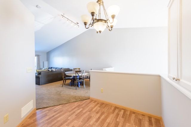 dining room with vaulted ceiling, track lighting, a chandelier, and hardwood / wood-style floors