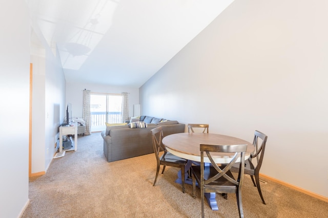 carpeted dining room with high vaulted ceiling