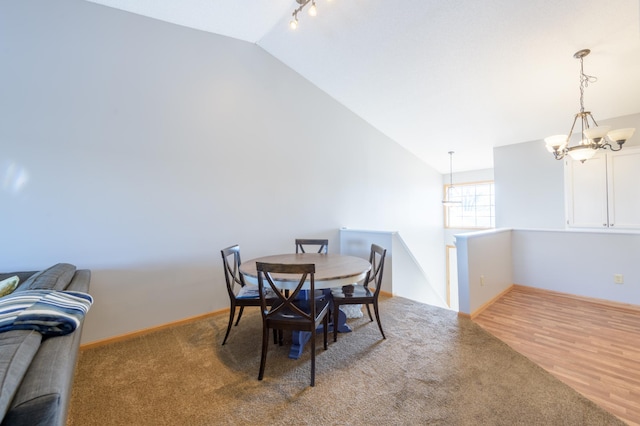 dining area with hardwood / wood-style floors, vaulted ceiling, a chandelier, and track lighting