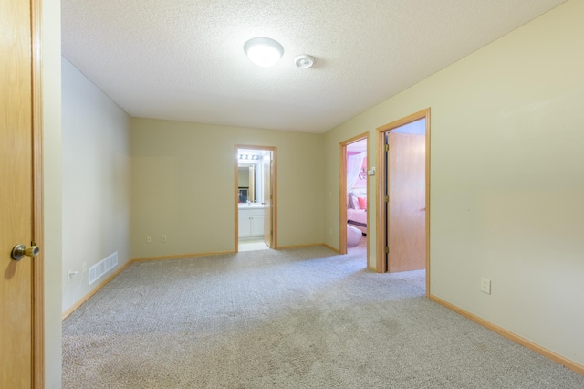 spare room featuring light colored carpet and a textured ceiling