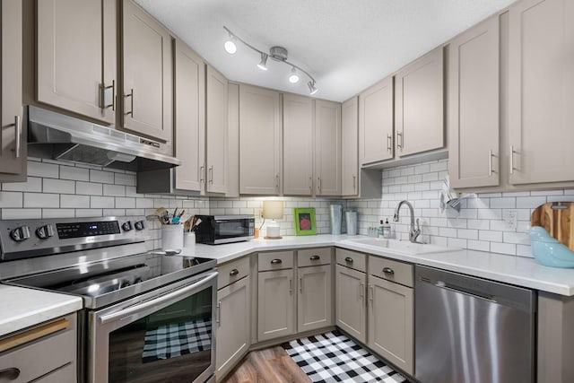 kitchen featuring sink, gray cabinetry, a textured ceiling, light wood-type flooring, and stainless steel appliances