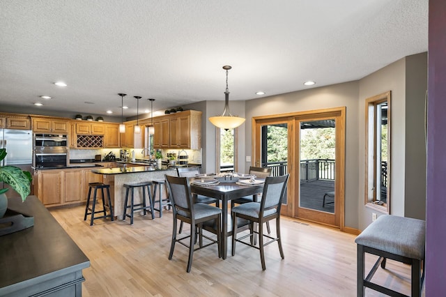 dining area featuring light wood-style flooring, visible vents, a textured ceiling, and recessed lighting