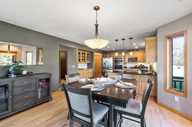 dining space with beverage cooler, baseboards, light wood-style flooring, a textured ceiling, and recessed lighting