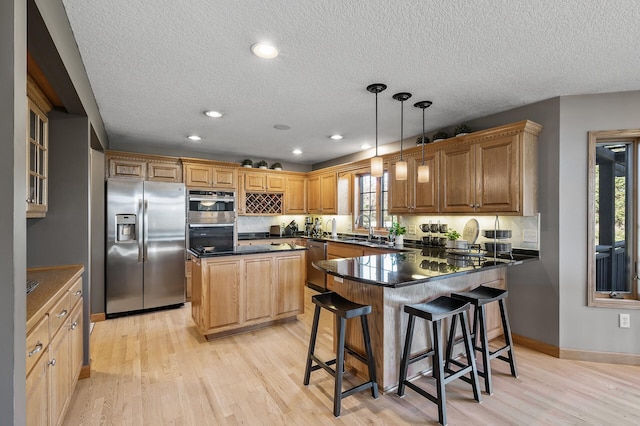 kitchen with dark countertops, stainless steel appliances, a peninsula, and a sink