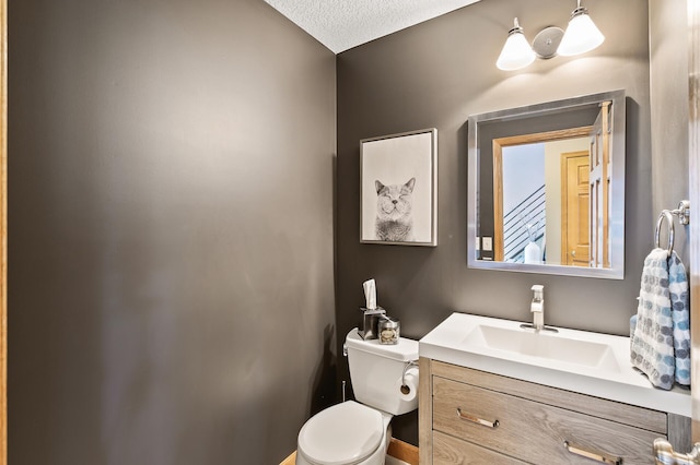 bathroom with a textured ceiling, vanity, and toilet