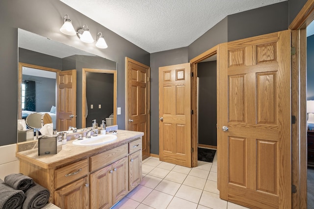 ensuite bathroom featuring a textured ceiling, connected bathroom, vanity, and tile patterned floors