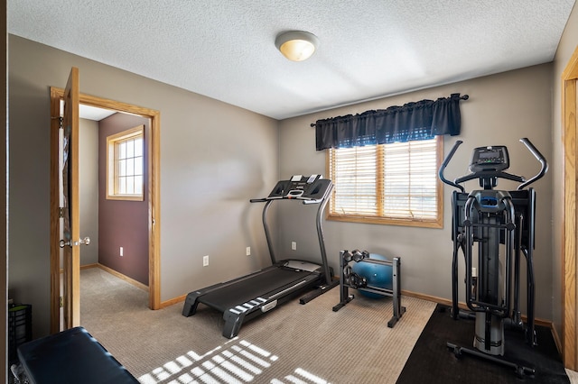 exercise area featuring a textured ceiling, carpet floors, and baseboards