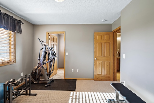 exercise area with a textured ceiling, carpet floors, and baseboards