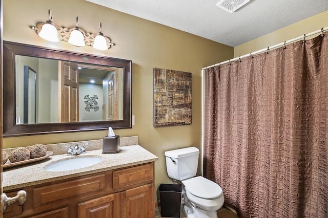 bathroom with visible vents, vanity, toilet, and a textured ceiling