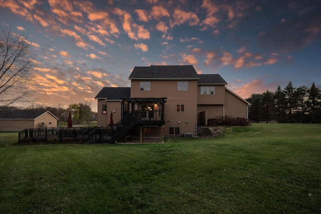 back of property at dusk featuring a yard, a wooden deck, and a pergola