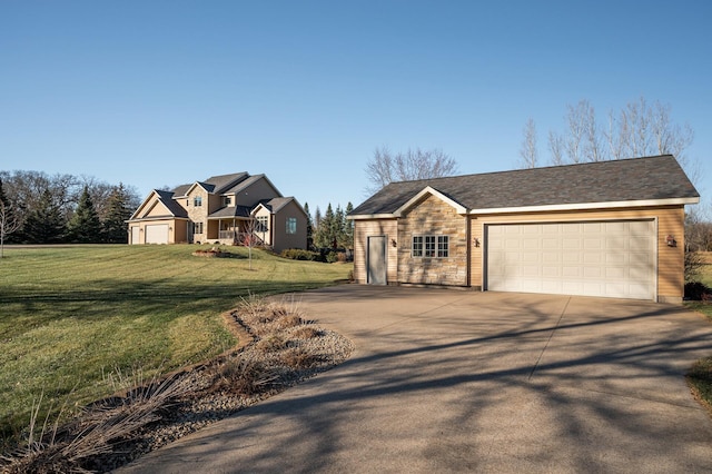 view of front of home featuring an outbuilding, an attached garage, concrete driveway, stone siding, and a front yard