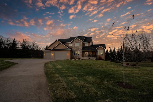 traditional home featuring driveway, stone siding, an attached garage, and a yard