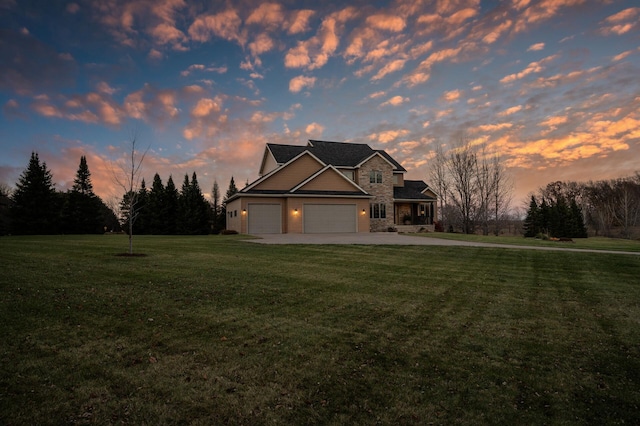 view of front of home with an attached garage, a yard, stone siding, and concrete driveway