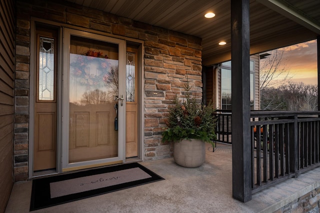 entrance to property with a porch and stone siding