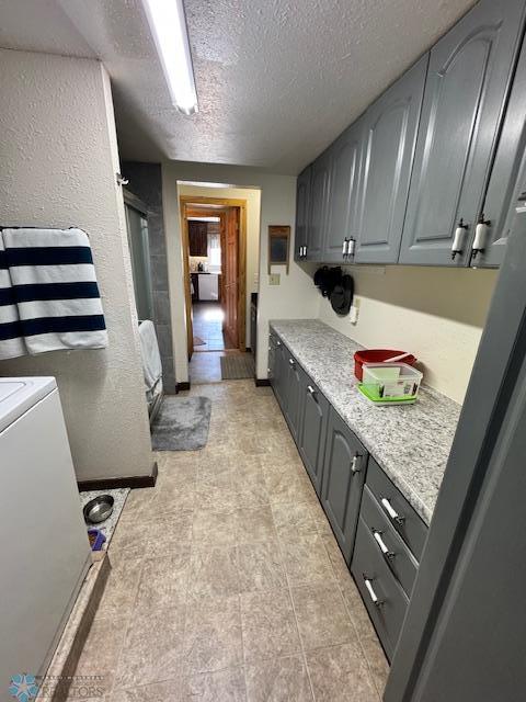 clothes washing area with cabinets and a textured ceiling