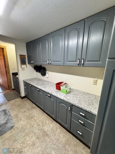 kitchen with gray cabinets, refrigerator, and a textured ceiling