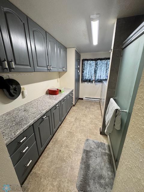 interior space featuring light stone countertops, a baseboard heating unit, and a textured ceiling