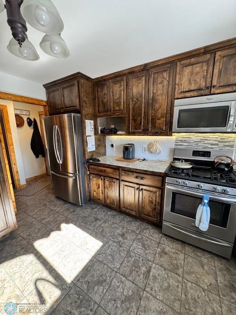 kitchen with stainless steel appliances, backsplash, and dark brown cabinetry