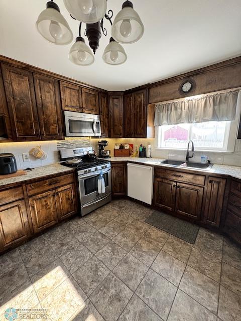 kitchen featuring pendant lighting, dark brown cabinetry, stainless steel appliances, and sink