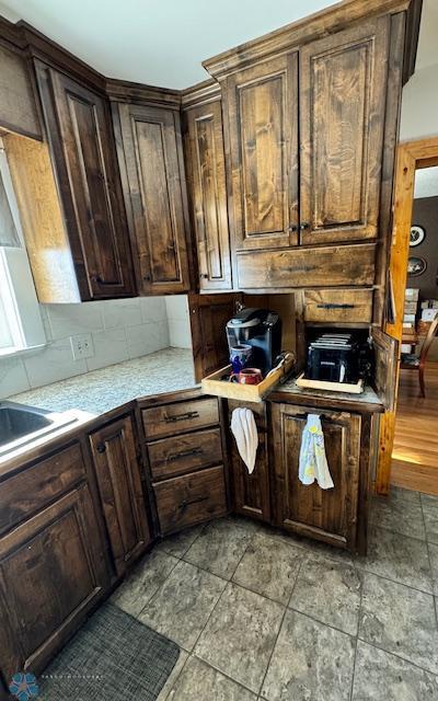 kitchen featuring tasteful backsplash, dark brown cabinetry, and sink