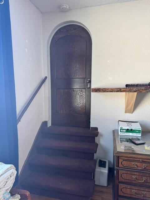 stairs with hardwood / wood-style floors and a textured ceiling