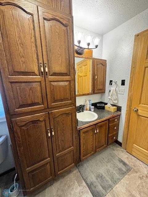 bathroom with vanity, toilet, and a textured ceiling