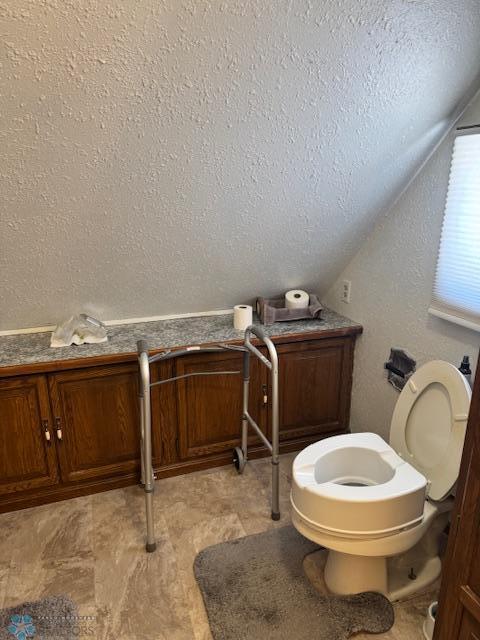 bathroom featuring vaulted ceiling, a textured ceiling, and toilet