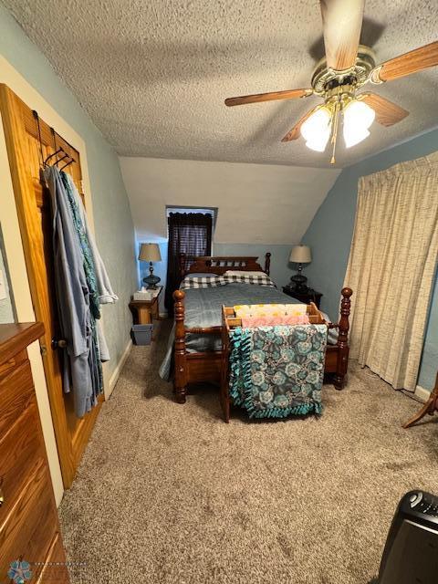 carpeted bedroom with ceiling fan, lofted ceiling, and a textured ceiling