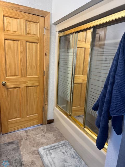 bathroom featuring combined bath / shower with glass door