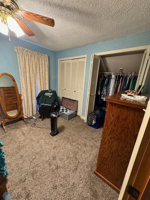 bedroom featuring ceiling fan, carpet flooring, a textured ceiling, and two closets