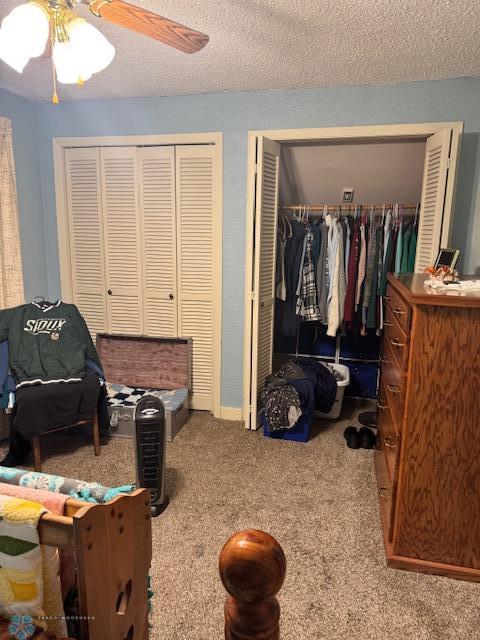 bedroom featuring multiple closets, ceiling fan, carpet flooring, and a textured ceiling